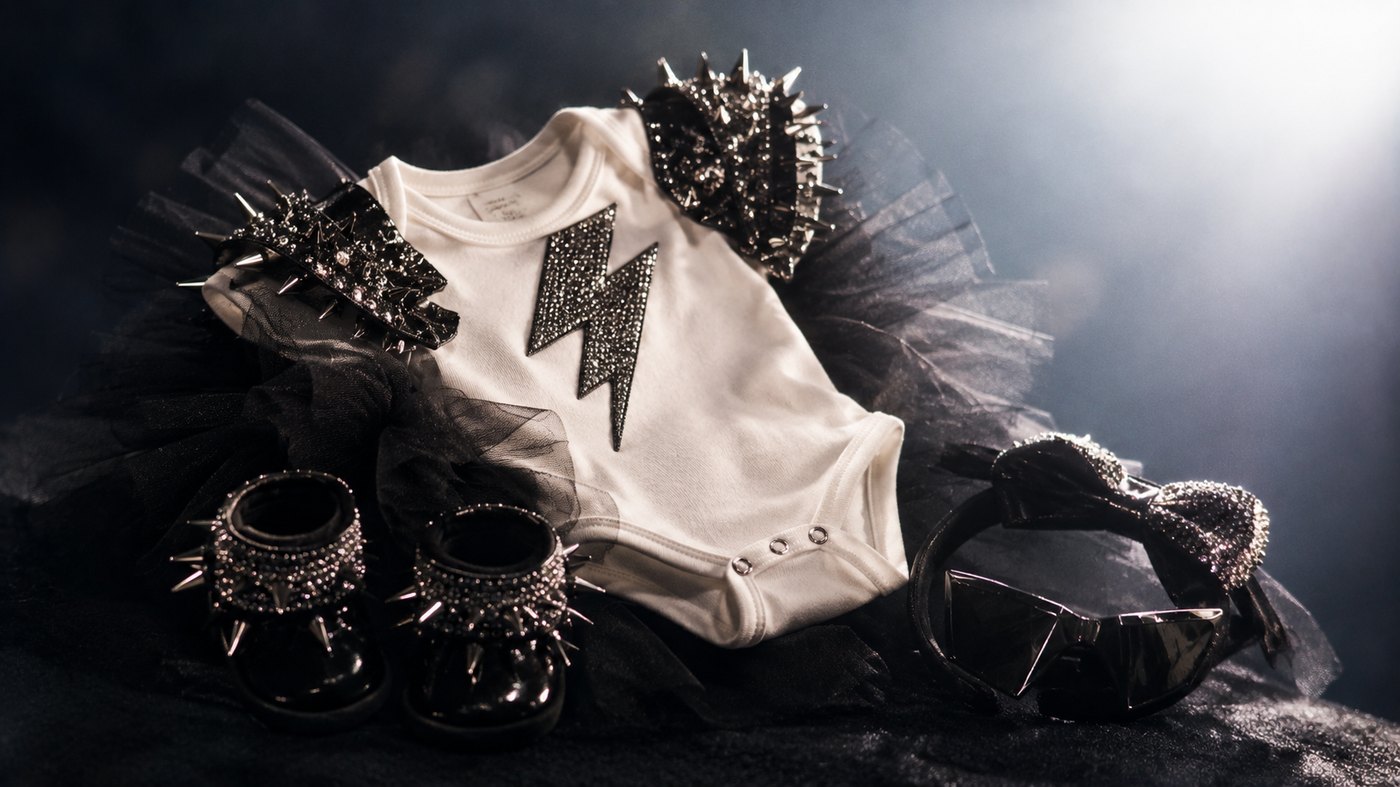 Baby clothes and accessories on a dark background with stage lighting